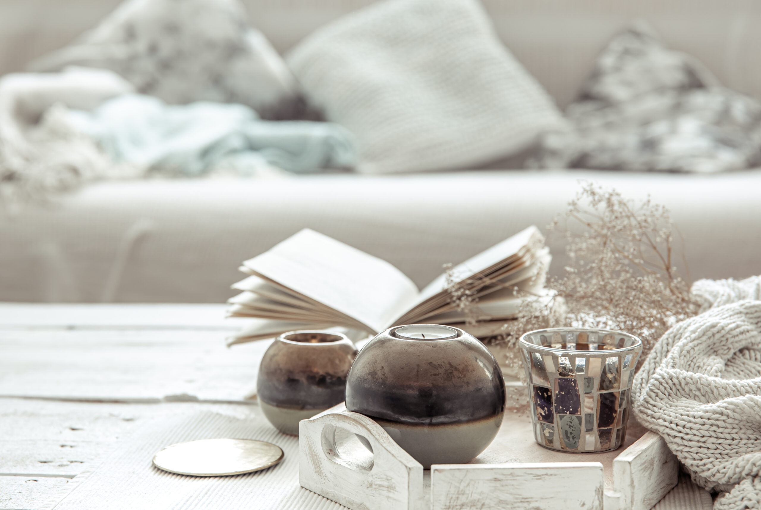 Mesa de salón decorada en estilo hygge con velas, un libro abierto y textiles claros que transmiten calma y confort. Mesa de salón decorada en estilo hygge con velas, un libro abierto y textiles claros que transmiten calma y confort.